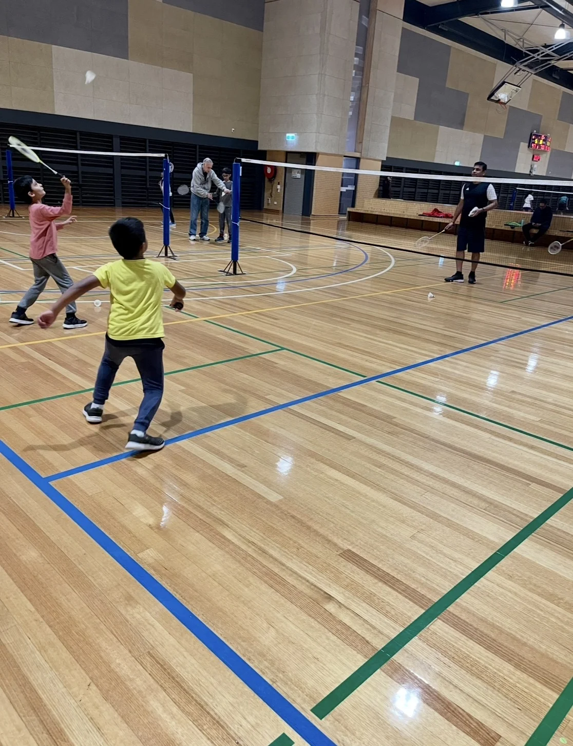 Junior players practising badminton on indoor courts
